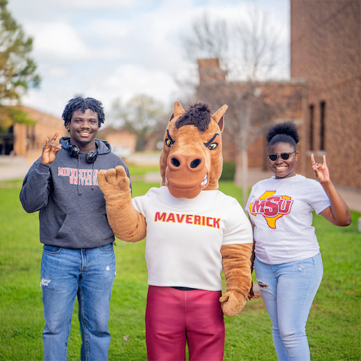 Two students pose with Maverick T. Mustang, the MSU Texas Mascot, while they hold up the Mustangs Hand Sign.